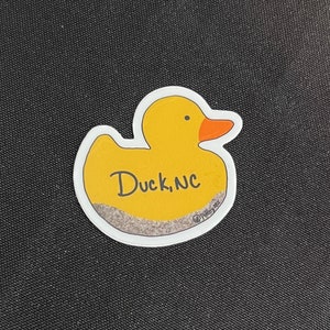 May include: Yellow rubber duck sticker with the text "Duck, NC" and a small copyright symbol with the text "Polkadot Fox".