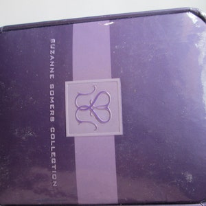 May include: A purple box with the text "SUZANNE SOMERS COLLECTION" and a logo of two intertwined hearts.