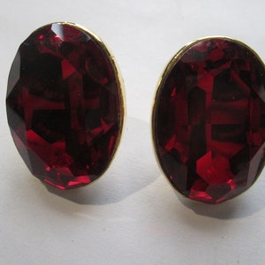 May include: A pair of red oval-shaped earrings with gold settings.