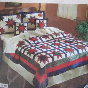 May include: A bed with a navy star quilt and matching pillow shams. The quilt features a grid pattern with red and navy stars on a white background, bordered by red, navy, and green stripes. The pillows have a similar star design.