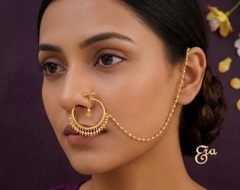 May include: A gold-colored nose ring with a circular design and dangling beads. A delicate chain extends from the nose ring to the ear, with a small charm hanging from the ear. The word "Era" is written in cursive script.