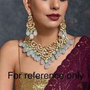 May include: A gold-toned necklace and earring set with clear and light blue accents. The jewelry features intricate detailing and a cascading design. The image includes the text "For reference only".