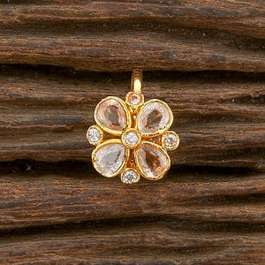 May include: A gold nose ring with a flower design featuring clear and light brown gemstones.