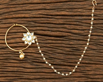 May include: A gold nose ring with a pearl chain and a flower-shaped pendant with clear stones.