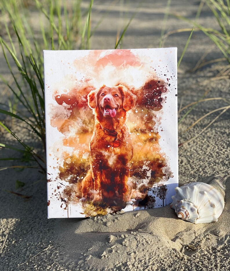 May include: A canvas print featuring a watercolor painting of a brown dog with its tongue out. The artwork has a white background with orange and brown paint splatters. A seashell rests on the sand next to the canvas.