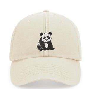 May include: A beige baseball cap with an embroidered black and white panda bear design.