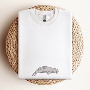 Può includere: Felpa bianca con un semplice disegno a linea di una balena beluga sul davanti.