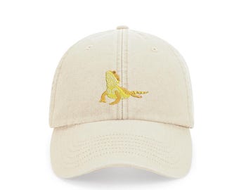 May include: A beige baseball cap with an embroidered yellow bearded dragon on the front.