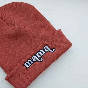 May include: A rust-colored beanie with the word "mama" embroidered in white.