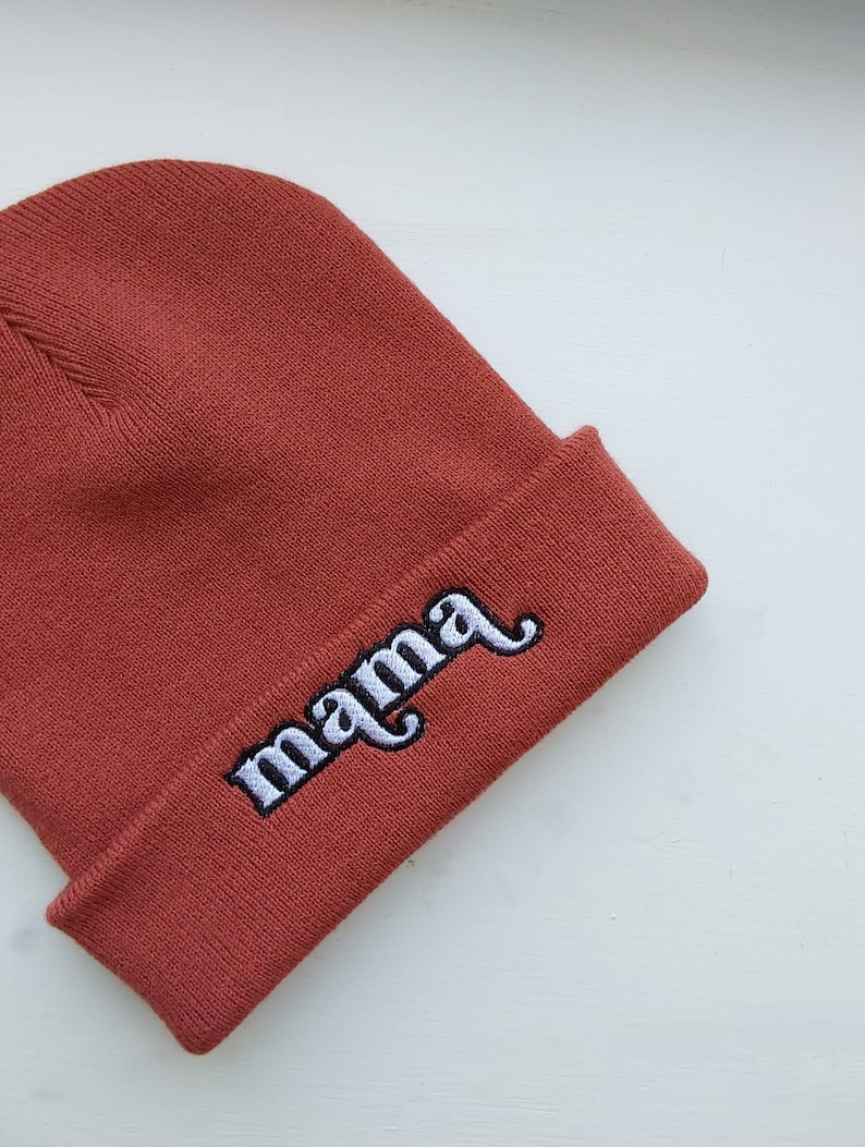 May include: A rust-colored beanie with the word "mama" embroidered in white.