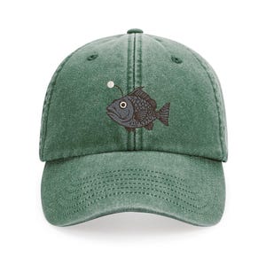May include: A green, vintage-style baseball cap with an embroidered image of a black anglerfish with a glowing lure.
