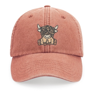 Könnte beinhalten: Eine rote Baseballkappe aus Baumwolle mit einem gestickten Bild einer braunen und schwarzen Highland-Kuh mit weißem Gesicht.