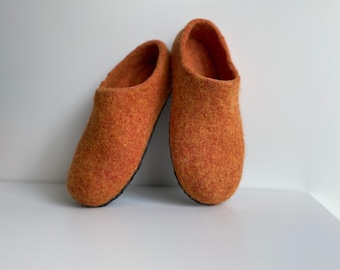 May include: A pair of orange felt slippers with a black sole.