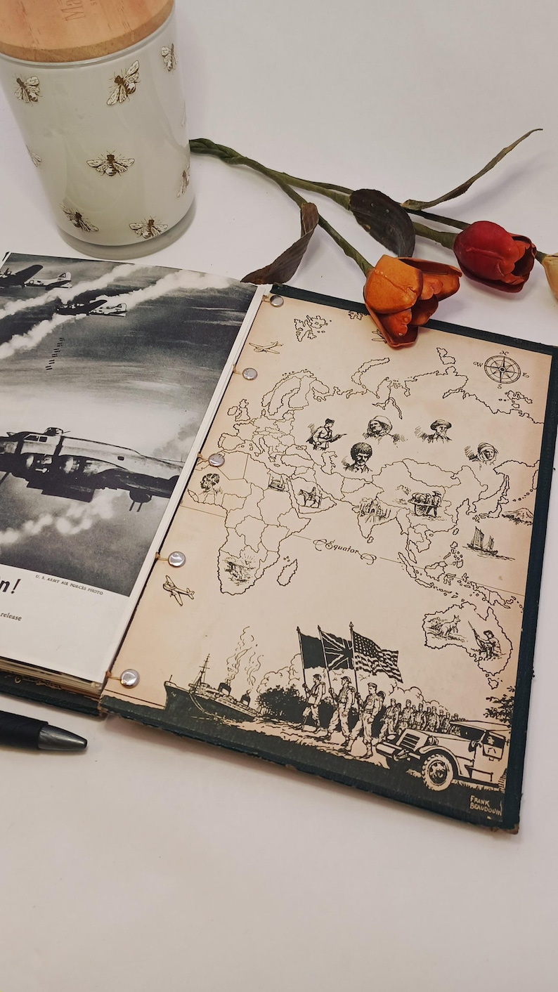 May include: A vintage map illustration featuring soldiers and a world map. A decorative jar with a wooden lid and bee pattern is in the background. The map is bound with metal rings and has a dark green border.