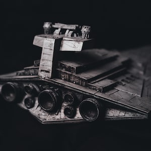 Puede incluir: Un modelo detallado de una nave espacial gris con una parte superior grande y plana y múltiples puertos de escape en la parte inferior.