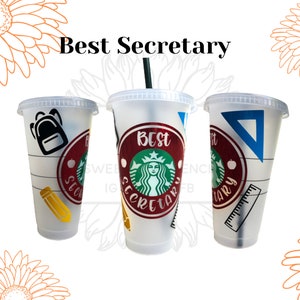 May include: Three white reusable cups with lids and straws. The cups are decorated with school-themed designs, including a backpack, pencil, ruler, and protractor. The middle cup has a red circle with the text "Best Secretary" and a green Starbucks logo.