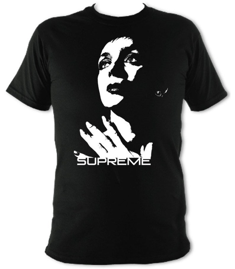 Op de afbeelding: Zwart T-shirt met een wit silhouet van een vrouwenhoofd en handen, met het woord "SUPREME" eronder gedrukt.
