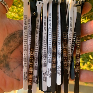 May include: A bundle of black and white cable ties with a ruler printed on them. The ruler measures in inches and half inches. The cable ties are labeled "SIZE & HALF SIZES" and have a patent pending number.