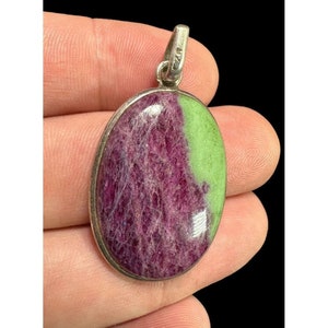 May include: Oval-shaped pendant with a green and purple gemstone set in silver. The gemstone has a swirling pattern of green and purple.