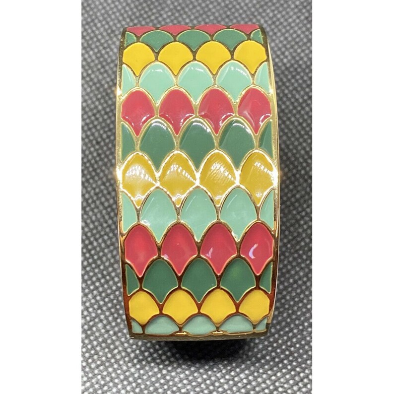 May include: A gold bangle bracelet with a colorful enamel design. The design features a repeating pattern of green, yellow, and red scales.