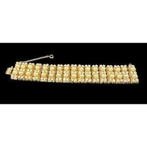 May include: A gold tone bracelet with a row of faux pearls and clear rhinestones.