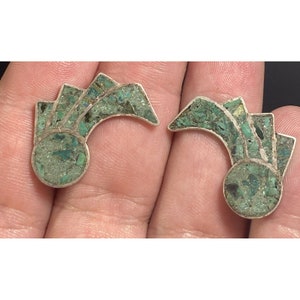 May include: A pair of silver earrings with green turquoise inlay. The earrings are shaped like a crescent moon with a circle at the bottom.