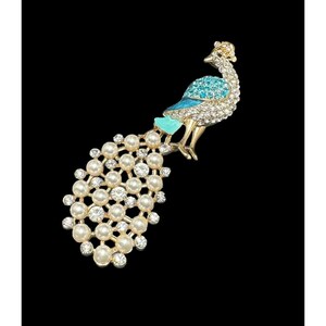 May include: A gold-tone peacock brooch with blue and green enamel accents. The peacock's tail is made of white pearls and rhinestones.