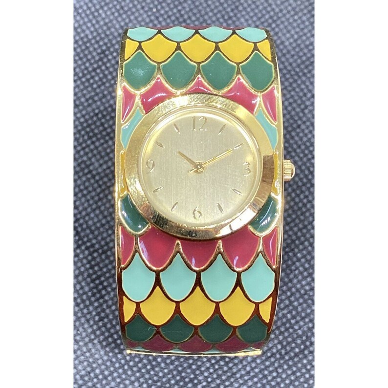 May include: A gold-tone wristwatch with a round face and a colorful, patterned band. The band features a repeating pattern of green, red, and yellow scales.