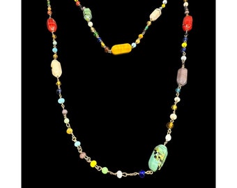 May include: A long, colorful necklace with a variety of glass beads, including yellow, green, blue, red, and white. The beads are strung on a gold chain.