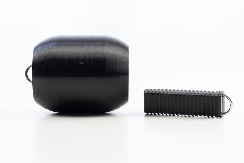 May include: Two black rubber weightlifting dumbbells with metal rings. The larger dumbbell is cylindrical and the smaller dumbbell is rectangular.