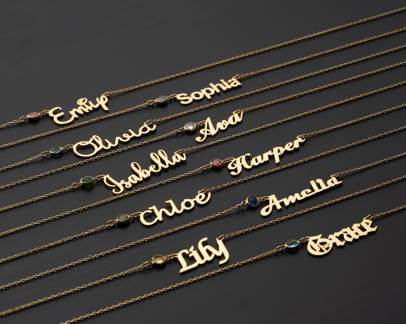 a collection of gold-colored necklaces with personalized names engraved on them, arranged in rows on a dark background.