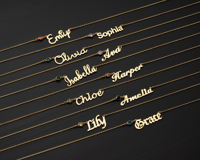 a collection of personalized name necklaces with gemstones, arranged in rows on a dark background.