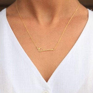May include: A gold necklace with a cursive nameplate that reads "Olivia".