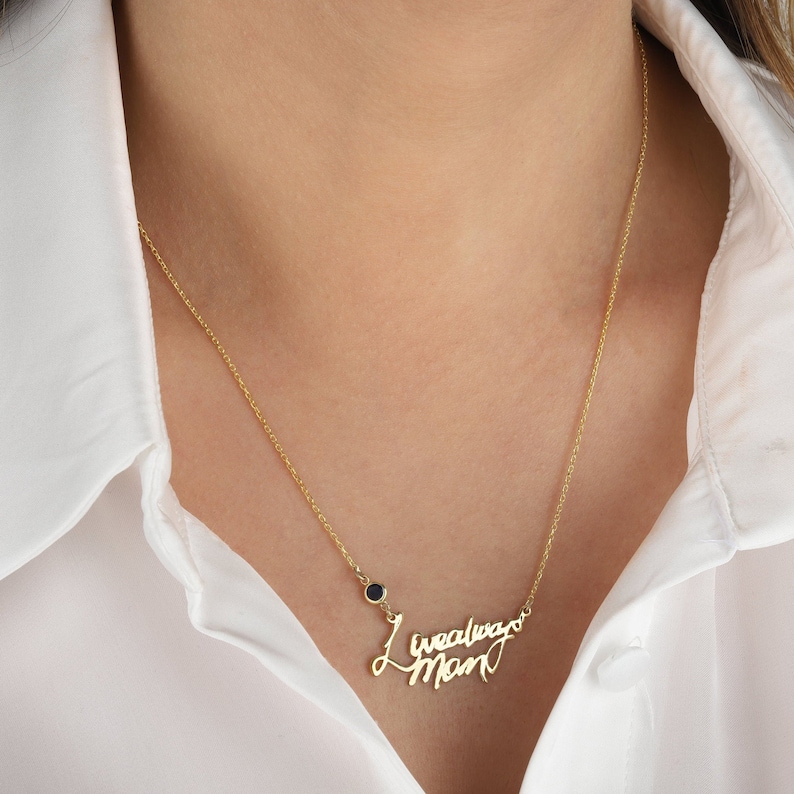 Op de afbeelding: Gouden ketting met een 'Always Mom' hanger in cursief schrift en een klein zwart edelsteentje.