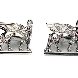 May include: A pair of silver cufflinks featuring a winged lion design. The lion is standing on a base and has its wings spread out.