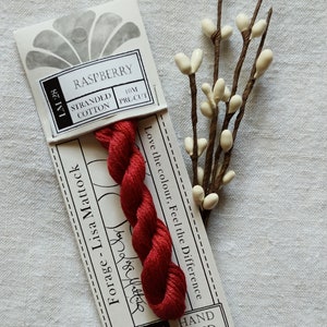 May include: A 10 metre spool of hand-dyed stranded cotton embroidery floss in a raspberry red colour. The floss is labelled "Forage - Lisa Mattock" and "CGT Hand Dyed".