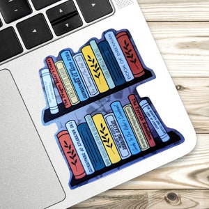 May include: A sticker of a bookshelf with a variety of books, including "The Dragon Rider's Codex", "The Sacrifice of Dragonkind", "The Tyrish Rebellion", and "Book of Brennan".
