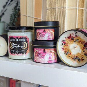 K&ouml;nnte beinhalten: Vier Sojawachskerzen in verschiedenen Gr&ouml;&szlig;en und Beh&auml;ltern. Die Kerzen sind mit "Starborn" beschriftet und zeigen ein Mond- und Sternenmotiv. Eine Kerze befindet sich in einem durchsichtigen Glasgef&auml;&szlig;, w&auml;hrend die anderen drei in schwarzen Metalldosen sind. Eine Kerze hat eine wei&szlig;e Wachsoberfl&auml;che mit getrockneten Blumen und Kr&auml;utern darauf.
