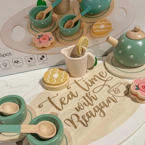 Könnte beinhalten: Ein Holz-Tee-Set mit einer grünen Teekanne, Tassen, Untertassen und Löffeln. Das Set ist auf einem Holztablett mit den Worten "Tea Time with Reagan" graviert angeordnet. Auf dem Tablett befinden sich auch Holzkekse und eine Zitronenscheibe.