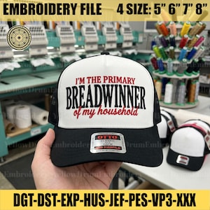Op de afbeelding: Een zwart-witte truckerpet met de geborduurde tekst I'M THE PRIMARY BREADWINNER of my household in zwarte en rode letters. De pet heeft een wit voorpaneel, zwarte mesh achterpanelen en een zwarte klep met een OTTO-merksticker.