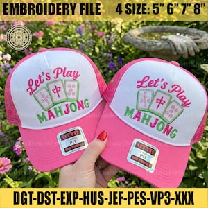 Peut inclure: Deux casquettes de type trucker roses et blanches avec des tuiles de mah-jong brodées et le texte Let's Play MAHJONG. Chaque casquette porte une étiquette sur la visière indiquant OTTO CLASSIC FIT MID PROFILE. Texte présent : EMBROIDERY FILE 4 SIZE: 5 6 7 8.