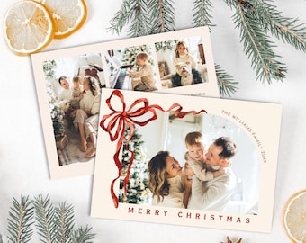 Könnte beinhalten: Zwei Weihnachtskarten mit Familienfotos. Eine Karte zeigt ein Aquarell-Rot-Schleifen-Design und die Worte "Merry Christmas". Die andere Karte hat drei Familienfotos. Die Karten liegen auf einer weißen Oberfläche mit Kiefern- und Zitronenscheiben.