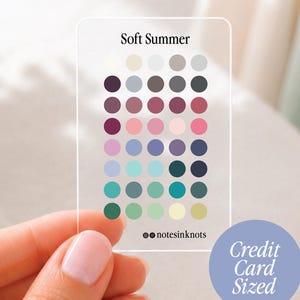 Op de afbeelding: Een doorzichtige kleurpaletkaart ter grootte van een creditcard met het label Soft Summer. Het bevat een raster van vijfendertig cirkelvormige kleurstaaltjes in diverse tinten blauw, groen, roze, paars en neutrale kleuren, met de tekst notesinkknots.