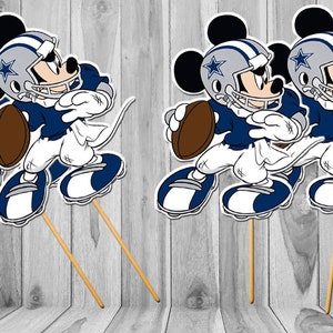 May include: Three cartoon Mickey Mouse figures wearing Dallas Cowboys football uniforms and helmets. Each figure is holding a football and is attached to a wooden stick. The figures are on a wooden background.
