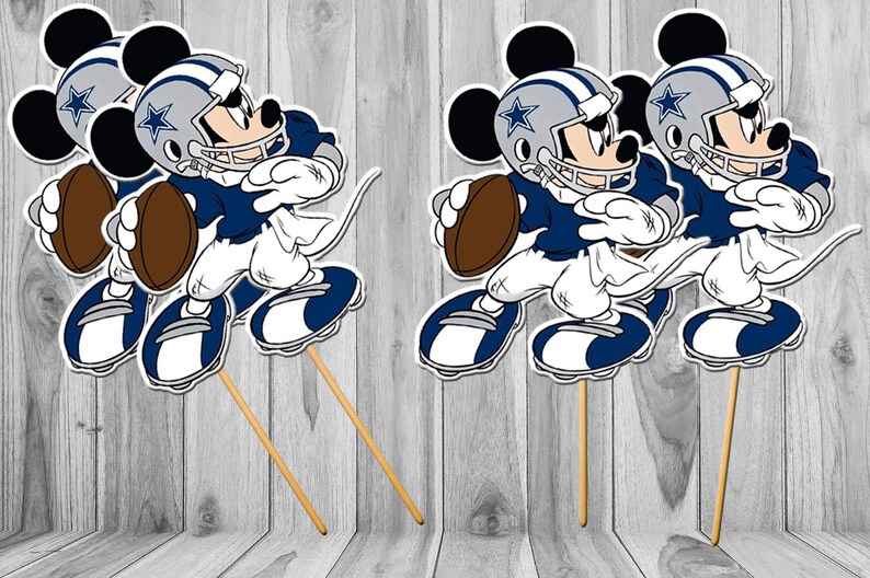 May include: Three cartoon Mickey Mouse figures wearing Dallas Cowboys football uniforms and helmets. Each figure is holding a football and is attached to a wooden stick. The figures are on a wooden background.