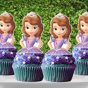 May include: Four purple and blue cupcakes with white stars and white pearl sprinkles topped with a princess character cupcake topper. The princess is wearing a purple dress and a crown.