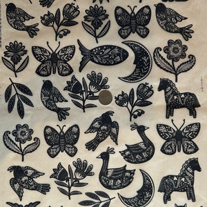 May include: A sheet of black and white patterned paper featuring a variety of images, including birds, butterflies, fish, cats, flowers, moons, and horses. The images are all cut out and ready for crafting projects.