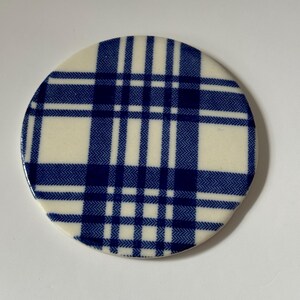 Może przedstawiać: Okrągły podkładka ceramiczna w niebiesko-białą kratę.