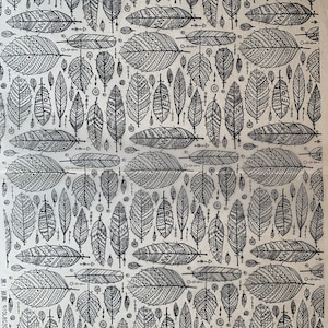 May include: A seamless pattern of black and white stylized feathers with geometric designs on a beige background.