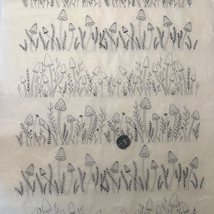 Peut inclure: Dessin au trait noir et blanc de champignons et d'herbe. Le dessin est répété cinq fois sur la page. Le texte "Shrooms" est en bas de la page.